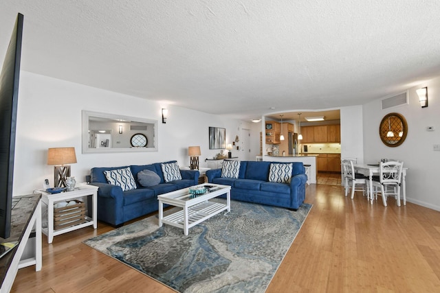 living room with a textured ceiling and light wood-style floors