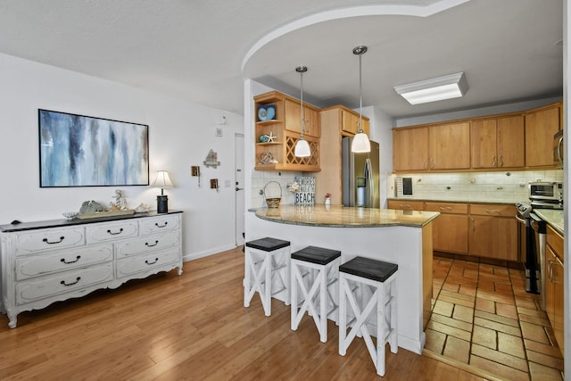 kitchen featuring stainless steel appliances, open shelves, a peninsula, and backsplash