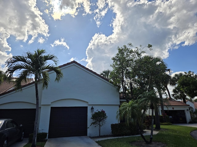 701 Sea Oats Dr Unit A-4, Juno Beach, FL 33408 - view of front of property featuring a garage, stucco siding, driveway, and a tiled roof