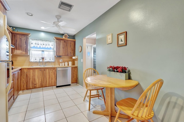 kitchen featuring stainless steel dishwasher, a sink, light countertops, ceiling fan, and light tile patterned flooring