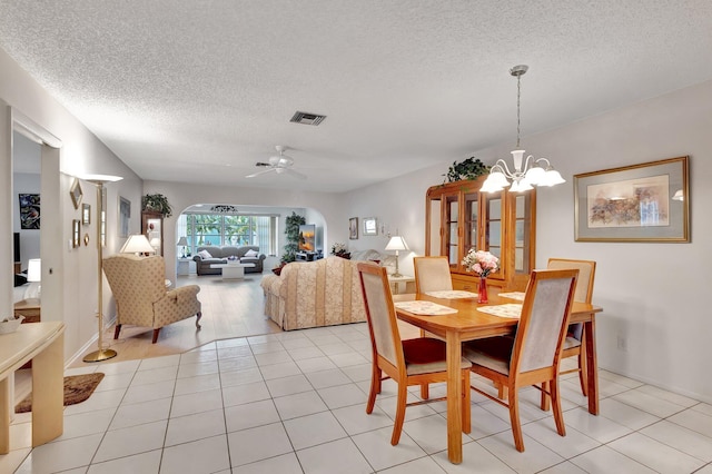 dining room featuring a textured ceiling, a chandelier, a ceiling fan, and light tile patterned flooring