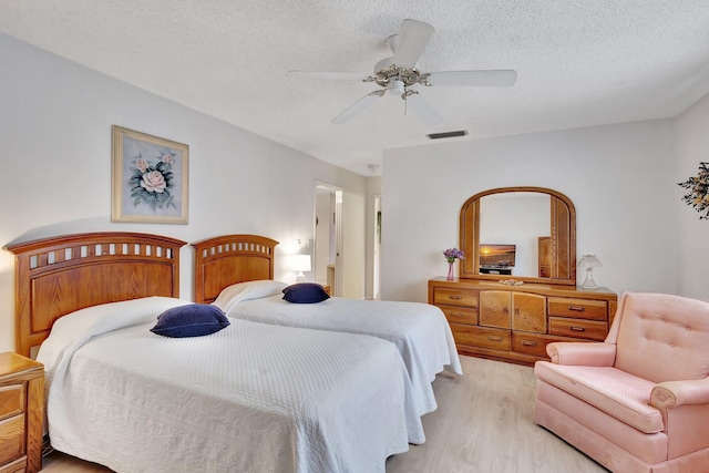bedroom with light wood finished floors, ceiling fan, and a textured ceiling