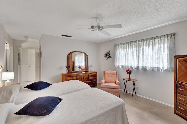 bedroom featuring light wood finished floors, baseboards, ceiling fan, and a textured ceiling
