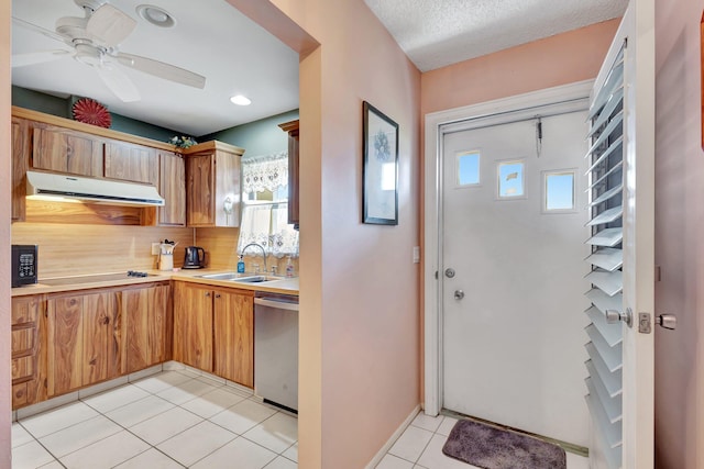 kitchen featuring range hood, black appliances, a sink, light countertops, and decorative backsplash