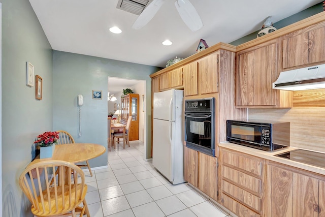kitchen with black appliances, under cabinet range hood, light tile patterned floors, light brown cabinetry, and light countertops
