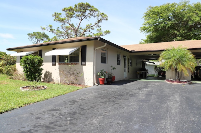 521 Sandpiper Cir, Delray Beach, FL 33445 - view of front of house featuring driveway, a carport, stucco siding, and a front yard