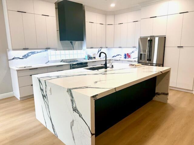 14838 Strand Ln, Delray Beach, FL 33446 - kitchen with stainless steel appliances, a sink, light wood-style floors, modern cabinets, and light stone countertops