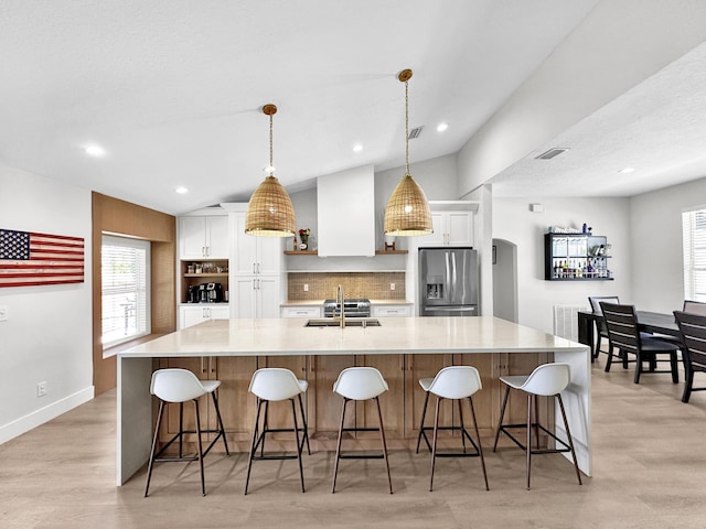 1726 SW Erie St, Port Saint Lucie, FL 34953 - kitchen with stainless steel fridge, lofted ceiling, white cabinetry, arched walkways, and a spacious island