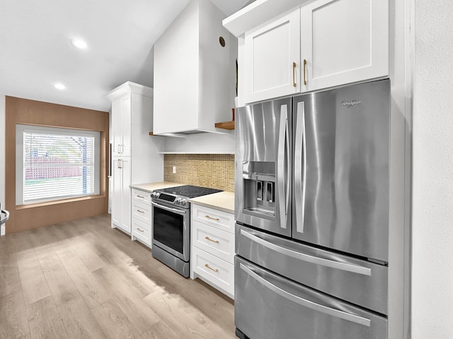 1726 SW Erie St, Port Saint Lucie, FL 34953 - kitchen with stainless steel appliances, light countertops, white cabinets, tasteful backsplash, and light wood finished floors