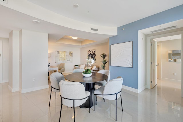 dining room with baseboards, light tile patterned floors, and a tray ceiling
