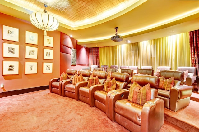 carpeted cinema with a tray ceiling and baseboards
