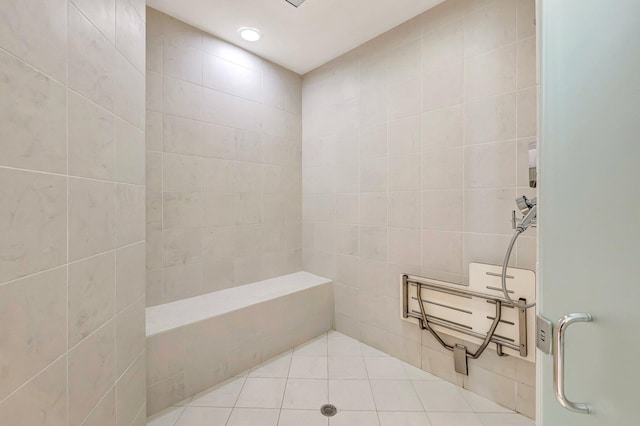bathroom with tiled shower, tile patterned flooring, and tile walls
