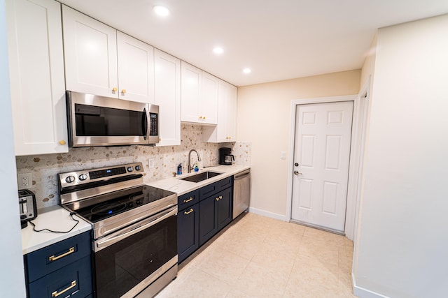 kitchen featuring appliances with stainless steel finishes, a sink, white cabinetry, tasteful backsplash, and light countertops