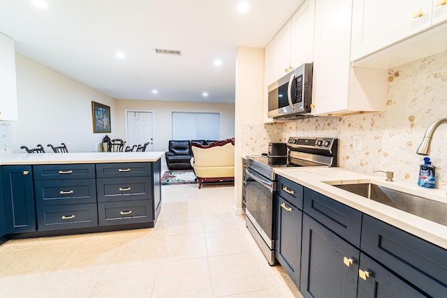 kitchen featuring stainless steel appliances, a sink, white cabinets, tasteful backsplash, and recessed lighting