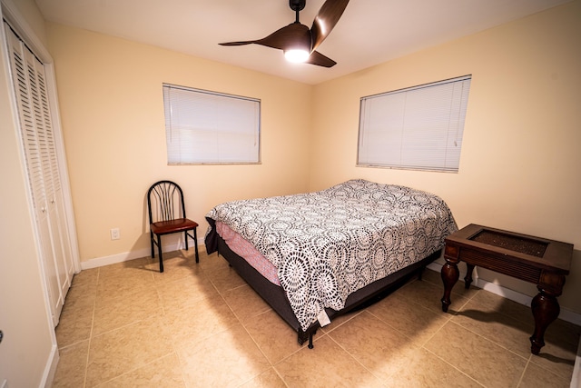 bedroom with a closet, a ceiling fan, light tile patterned flooring, and baseboards