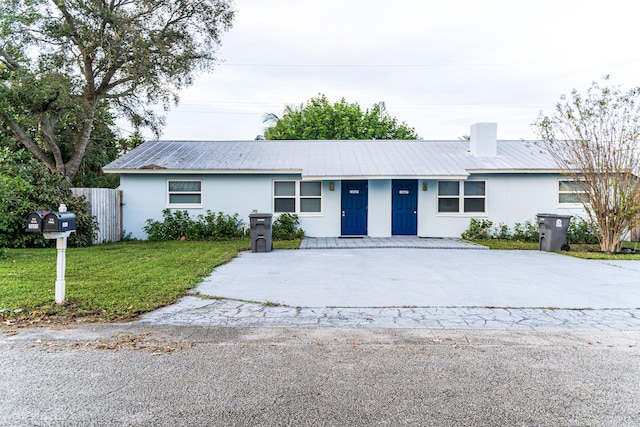 ranch-style home with stucco siding, driveway, and metal roof