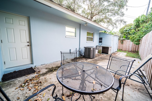 view of patio featuring central AC unit, outdoor dining space, and a fenced backyard