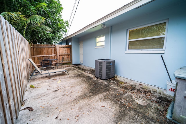 view of side of property featuring central AC, fence, stucco siding, and a patio