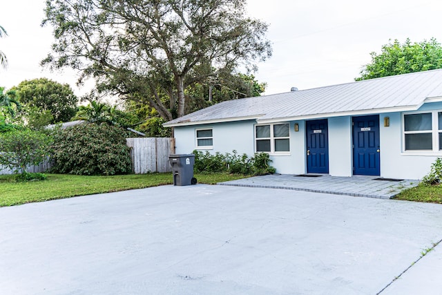 single story home with stucco siding, fence, a porch, and metal roof