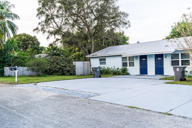 ranch-style house with fence, stucco siding, driveway, and metal roof