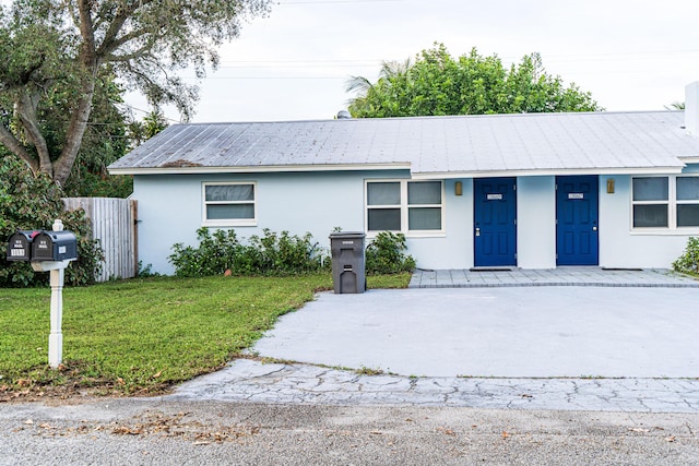 ranch-style house with stucco siding, metal roof, a porch, and concrete driveway