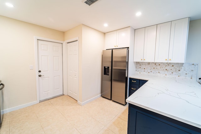 kitchen with stainless steel refrigerator with ice dispenser, light stone countertops, white cabinets, recessed lighting, and baseboards