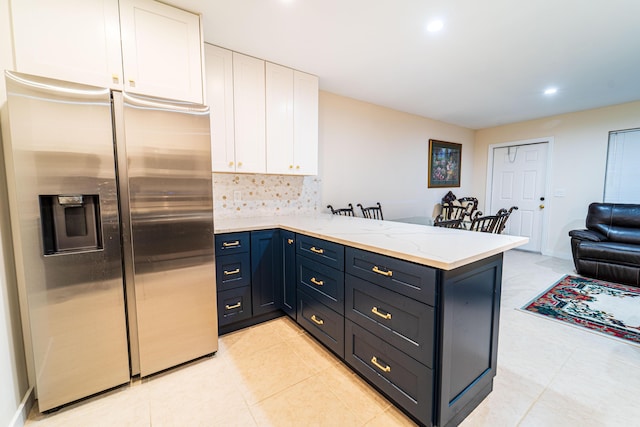kitchen with stainless steel fridge, white cabinets, a peninsula, tasteful backsplash, and recessed lighting