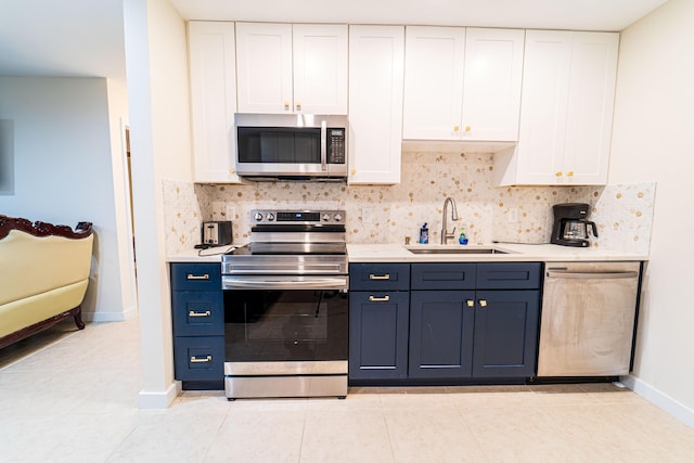 kitchen featuring appliances with stainless steel finishes, a sink, white cabinets, and backsplash