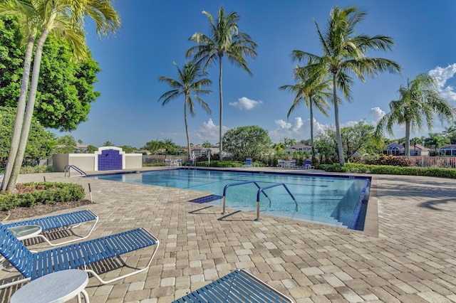 community pool with a patio area and fence