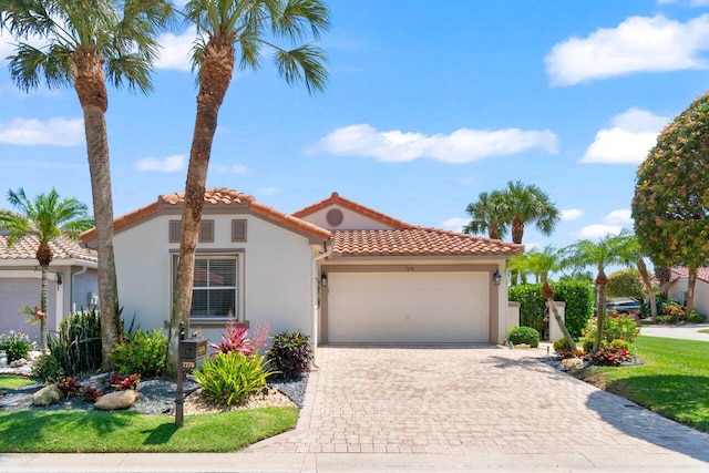 mediterranean / spanish-style home with stucco siding, a tile roof, an attached garage, and driveway