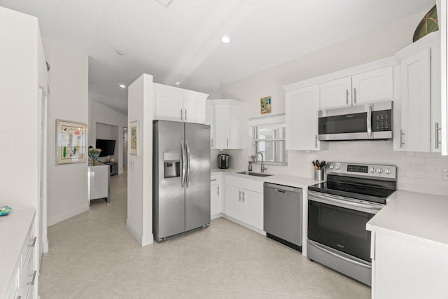 kitchen with stainless steel appliances, a sink, decorative backsplash, white cabinets, and light countertops