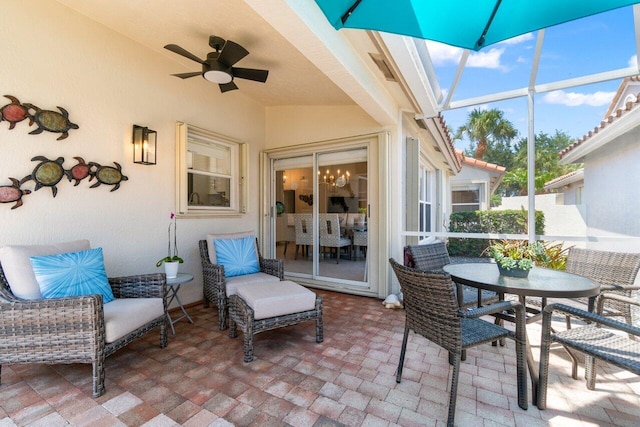 view of patio featuring ceiling fan, glass enclosure, and outdoor dining space