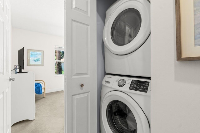laundry room with stacked washing machine and dryer and light tile patterned floors