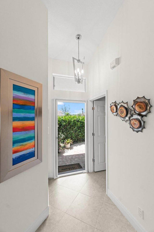 entryway featuring baseboards, a chandelier, and tile patterned floors