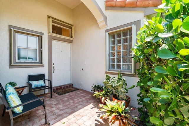 property entrance with stucco siding and a patio area