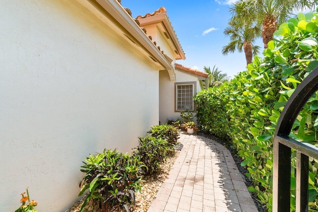 view of side of property featuring stucco siding and a tile roof