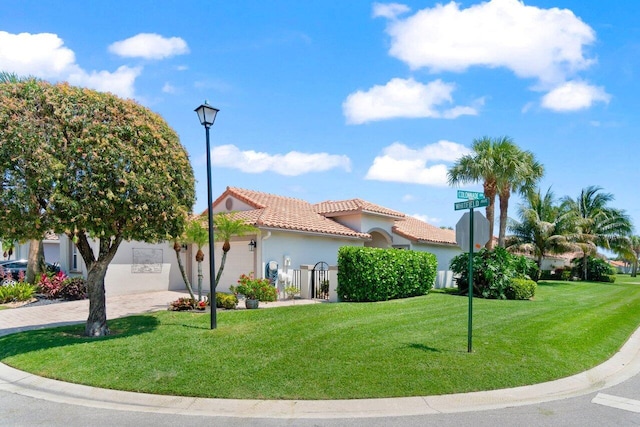mediterranean / spanish house featuring a tiled roof, a front yard, stucco siding, and a gate