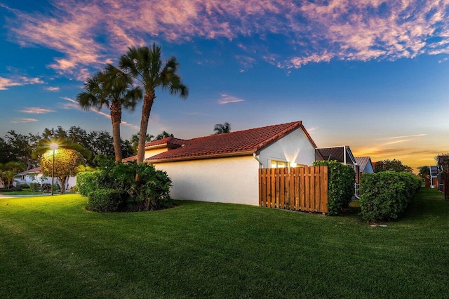 property exterior at dusk with stucco siding and a tiled roof