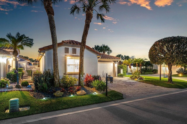 mediterranean / spanish-style home with driveway, a tile roof, an attached garage, and stucco siding