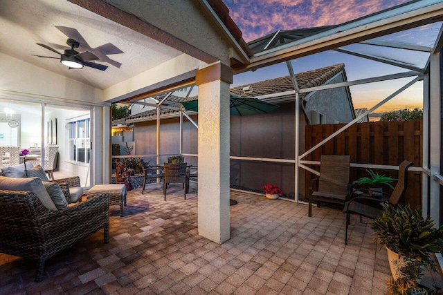 view of patio with ceiling fan, outdoor dining area, and glass enclosure