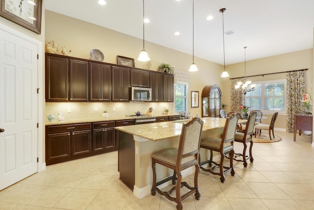 4885 SW Gossamer Cir, Palm City, FL 34990 - kitchen featuring stainless steel microwave, a chandelier, a breakfast bar, light stone countertops, and light tile patterned flooring