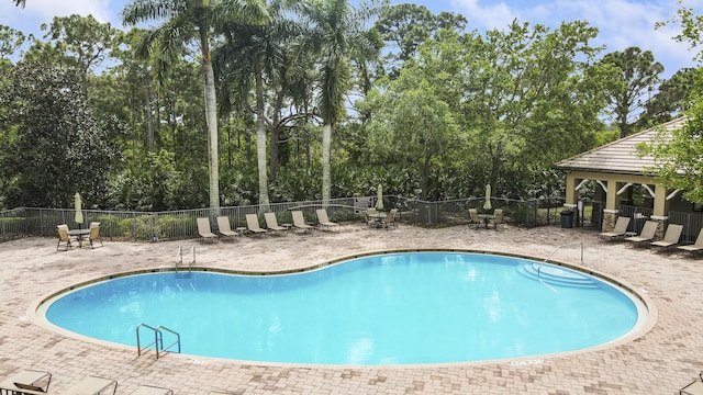 4885 SW Gossamer Cir, Palm City, FL 34990 - community pool with a gazebo, fence, a patio area, and view of wooded area