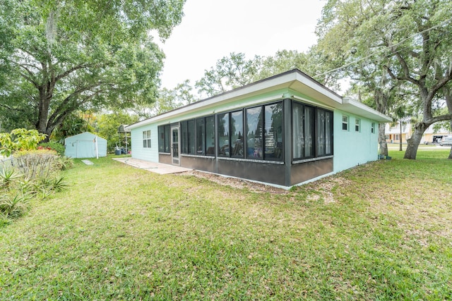 7302 Banyan St, Fort Pierce, FL 34951 - rear view of property featuring an outbuilding, a sunroom, a yard, a storage unit, and a patio