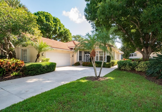 view of front of property with a tiled roof, an attached garage, driveway, stucco siding, and a front yard