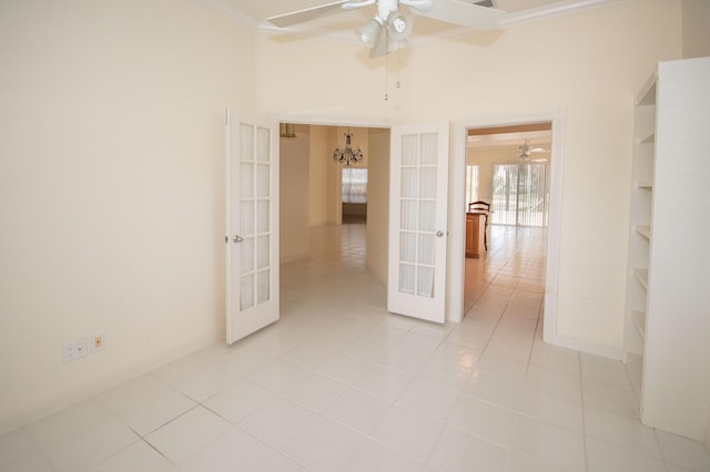 empty room with french doors, a ceiling fan, ornamental molding, light tile patterned floors, and baseboards
