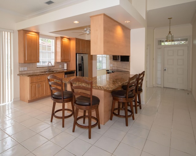 kitchen with stainless steel refrigerator with ice dispenser, a sink, backsplash, healthy amount of natural light, and ornamental molding