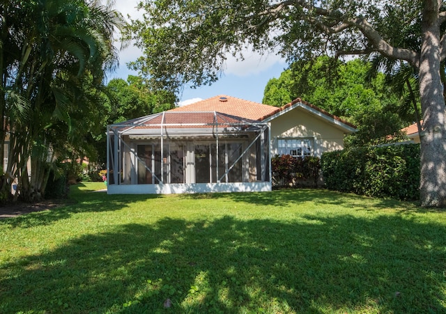 back of property with a lawn and a tile roof