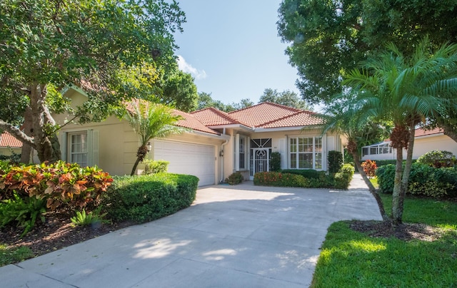 mediterranean / spanish home featuring a tile roof, stucco siding, a garage, and driveway