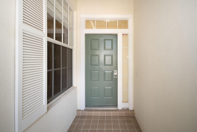 view of exterior entry with stucco siding and a porch