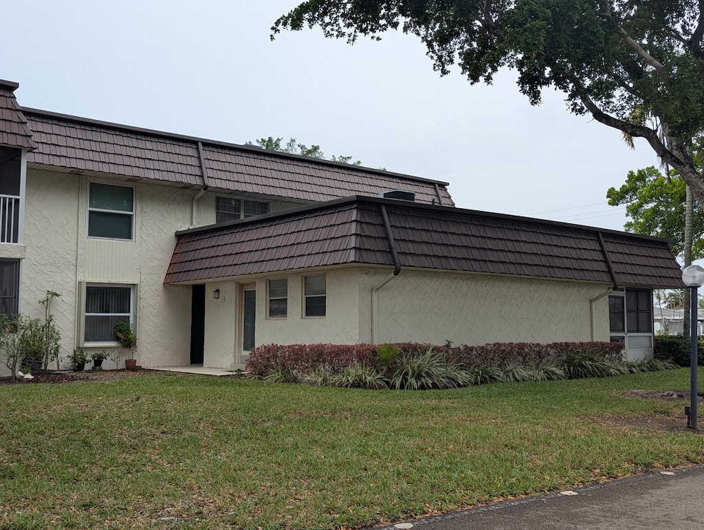 view of side of property with mansard roof and stucco siding